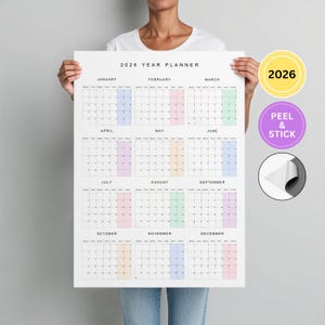 May include: A 2026 year planner with a white background, featuring monthly calendars in a grid layout. Each month has a different pastel color. The text "2026 YEAR PLANNER" is at the top.
