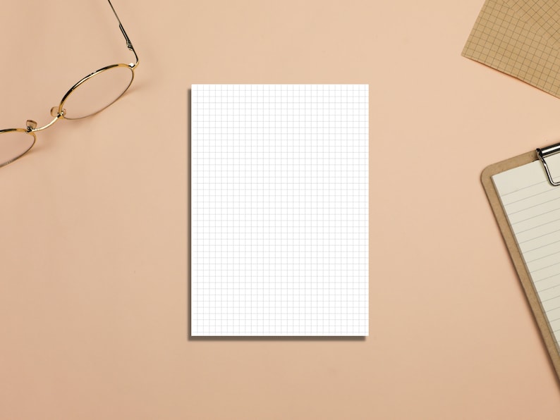 May include: A white gridded notepad on a light brown surface with a pair of gold-rimmed glasses and a brown clipboard with lined paper.