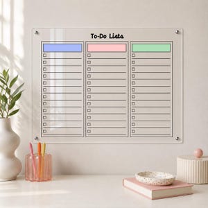 May include: A clear acrylic wall-mounted dry erase board with the text To-Do Lists printed at the top. The board features three vertical columns with blue, pink, and green headers, each containing rows of checkboxes and lines for writing tasks.