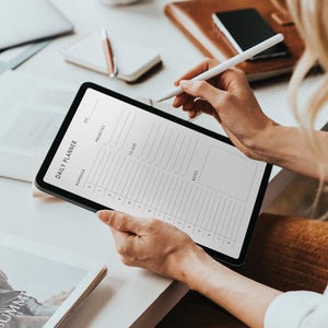 Printed half-letter daily planner sheet featuring a structured schedule layout, task list, and notes area, lying on a flat surface with soft natural lighting and a neutral tone.