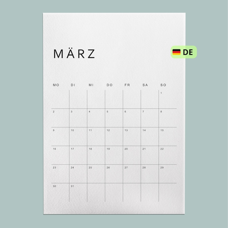 Kalender 2026 deutschsprachig, minimalistisches Design mit Monatsübersicht, auf weißem A4-Blatt gedruckt, liegt auf heller Holzoberfläche, natürliche Lichtverhältnisse.