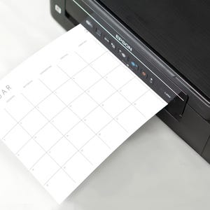 Hochauflösende A5 Kalenderseite 2026 in Querformat mit minimalistischer grauer Schrift und Linien auf weißem Papier, leicht geneigt auf neutralem Hintergrund.
