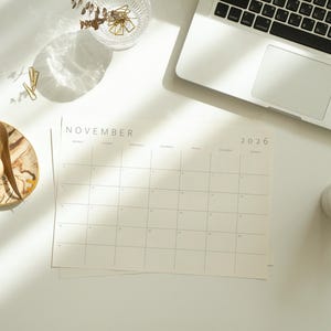 Overhead shot of a 2026 calendar month printed on US Letter paper, landscape format, showing minimalist thin grey lines and clear modern font for dates.