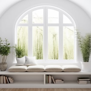 Peut inclure: Un banc de fenêtre blanc avec une grande fenêtre cintrée, deux plantes en pot et des étagères blanches encastrées de chaque côté. Le banc de fenêtre a un coussin beige et deux coussins blancs.