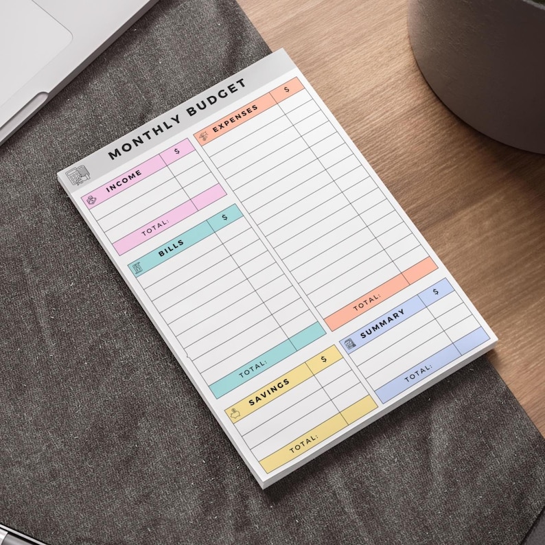 Monthly finance planner notepad with hand-drawn-style icons and soft pastel headers labeling income, expenses, savings, and summary, set on a clean white background.