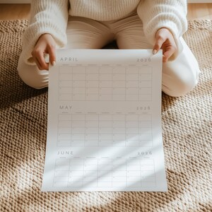 A printed page of the 2026 quarterly calendar showing January, February, and March with thin grey font and grid lines, portrait layout on white paper against a neutral colored background.