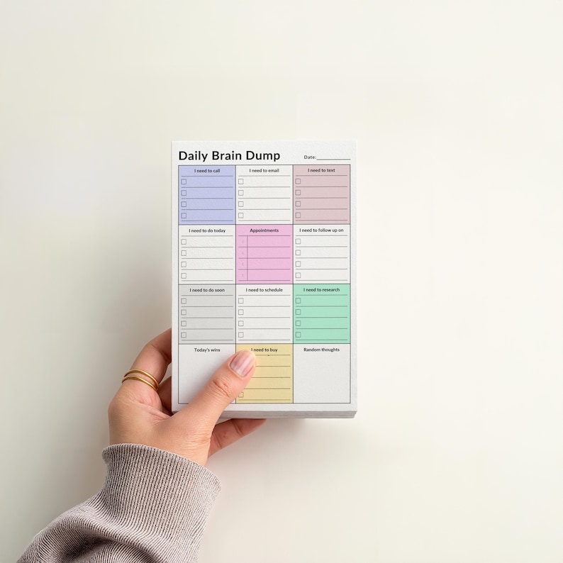 Hand holding a 4x6 ADHD sticky notes planner pad with shaded sections for tasks, calls, appointments, and brain dump, compact size with color-coded layout for focus and daily organization.