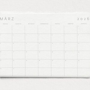 Nahaufnahme einer einzelnen Kalenderseite 2026 in A3 Querformat mit minimalistischen grauen Linien und klarer Typografie auf weißem Papier vor neutralem Hintergrund.