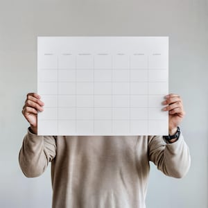 Può includere: Un calendario da parete rettangolare bianco con una griglia a sette colonne etichettate da lunedì a domenica in testo nero senza grazie. Il calendario presenta cinque righe orizzontali di caselle vuote per una pianificazione organizzata.