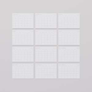 All 12 months of a minimalist aesthetic 2026 calendar in landscape format, white paper with subtle grey lines and elegant modern font, flat on a medium-light desk surface.