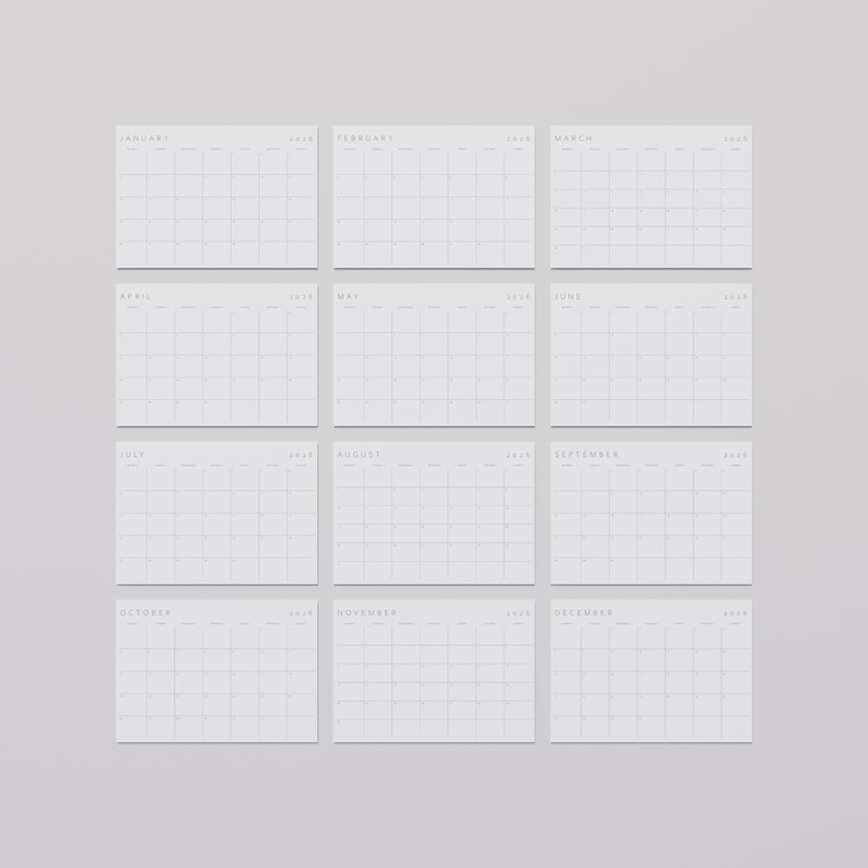 All 12 months of a minimalist aesthetic 2026 calendar in landscape format, white paper with subtle grey lines and elegant modern font, flat on a medium-light desk surface.