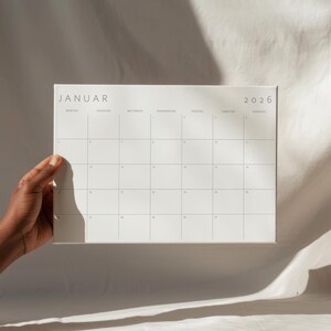 Übersichtliche Monatsansicht 2026 auf A2 Querformat Kalenderseite mit minimalistischer grauer Schrift und Linien auf weißem Papier, auf hellem Untergrund platziert.