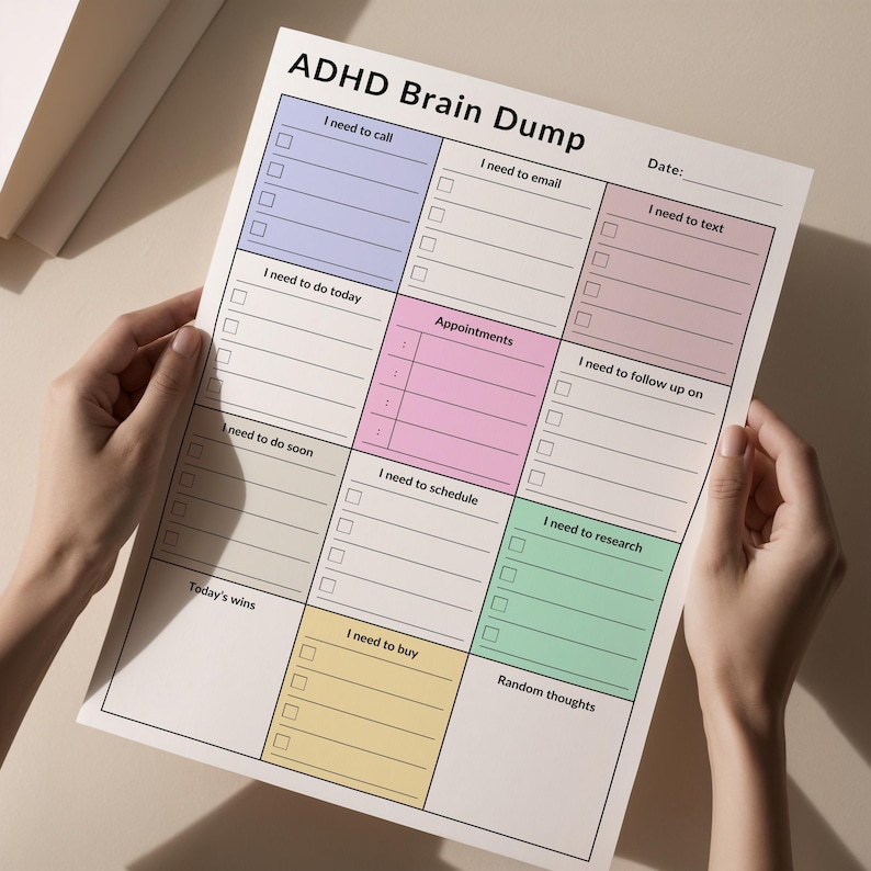 A person holding a printed ADHD brain dump planner, showing sections for tasks, phone calls, and notes. The planner is in portrait orientation and placed against a neutral, soft background for clarity.