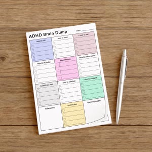 A person holding a 4x6 inch ADHD planner sticky note sheet, showing a structured daily layout with visually distinct sections for notes, tasks, calls, and appointments on matte white paper.