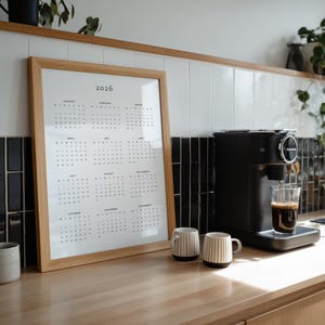 Printable 2026 year at a glance calendar displayed on US Letter paper with portrait layout, showing all months in a single page grid, minimalist font style, photographed on a simple desk background