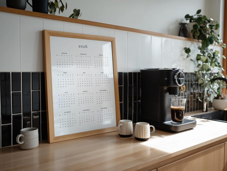 Printable 2026 year at a glance calendar displayed on US Letter paper with portrait layout, showing all months in a single page grid, minimalist font style, photographed on a simple desk background