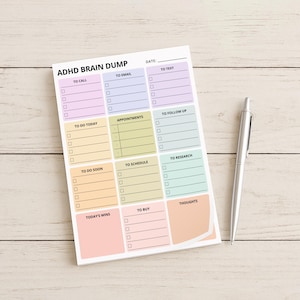 Detail image of a brain dump planner sticky note pad attached to a notebook, showing a single page with labeled areas and checkboxes for organizing scattered thoughts in one place.