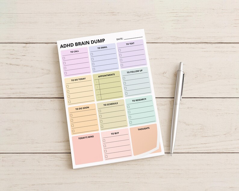 Detail image of a brain dump planner sticky note pad attached to a notebook, showing a single page with labeled areas and checkboxes for organizing scattered thoughts in one place.