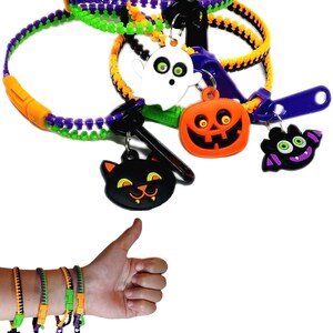 Puede incluir: Conjunto de cuatro pulseras de cremallera de Halloween con abalorios. Cada pulsera est&aacute; hecha de cinta de cremallera naranja, verde y morada. Los abalorios son un fantasma, una calabaza, un murci&eacute;lago y un gato negro.
