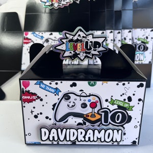 May include: Black and white favor box with a video game controller and the words "Level Up!" and "Davidramon" printed on it. The box has a black handle and a white background with black polka dots.