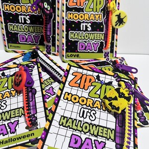 Puede incluir: Cuatro etiquetas de regalo con tem&aacute;tica de Halloween con tiradores de cremallera adjuntos. Las etiquetas son negras con rayas moradas, verdes y naranjas. El texto en las etiquetas dice "Zip Zip Hooray! It's Halloween Day".