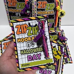 Puede incluir: Un conjunto de tarjetas con tem&aacute;tica de Halloween con un cierre de cremallera adjunto. Las tarjetas est&aacute;n decoradas con colores naranja, verde, morado y negro. El texto en las tarjetas dice "Zip Zip Hooray! It's Halloween Day".