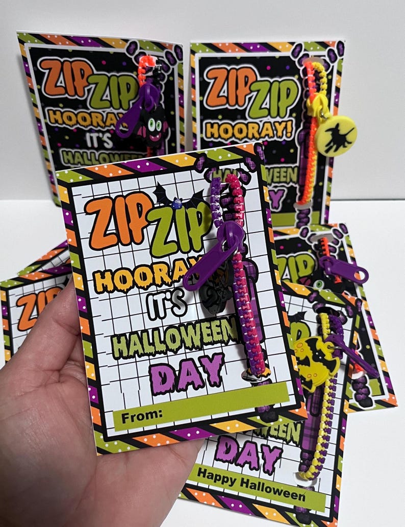 Puede incluir: Un conjunto de tarjetas con tem&aacute;tica de Halloween con un cierre de cremallera adjunto. Las tarjetas est&aacute;n decoradas con colores naranja, verde, morado y negro. El texto en las tarjetas dice "Zip Zip Hooray! It's Halloween Day".