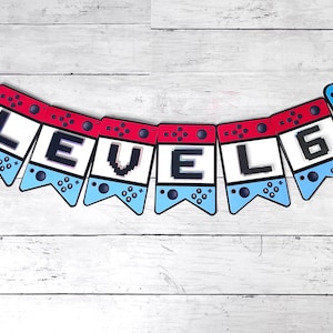 Puede incluir: Una pancarta roja y azul con la palabra "LEVEL 6" en letras blancas. La pancarta está decorada con imágenes de mandos de videojuegos y las palabras "GAME OVER".