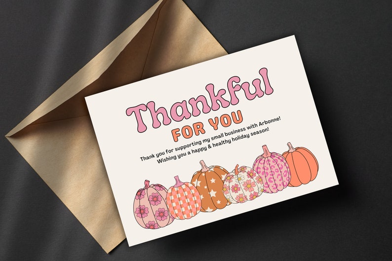May include: A white card with the text "Thankful for you" in pink and orange letters. The card has a fall theme with five pumpkins with different patterns in pink, orange, and white.