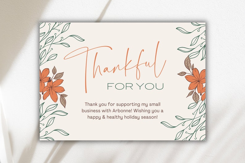 May include: A beige card with a handwritten message that says "Thankful for you". The card is decorated with green leaves and orange flowers.