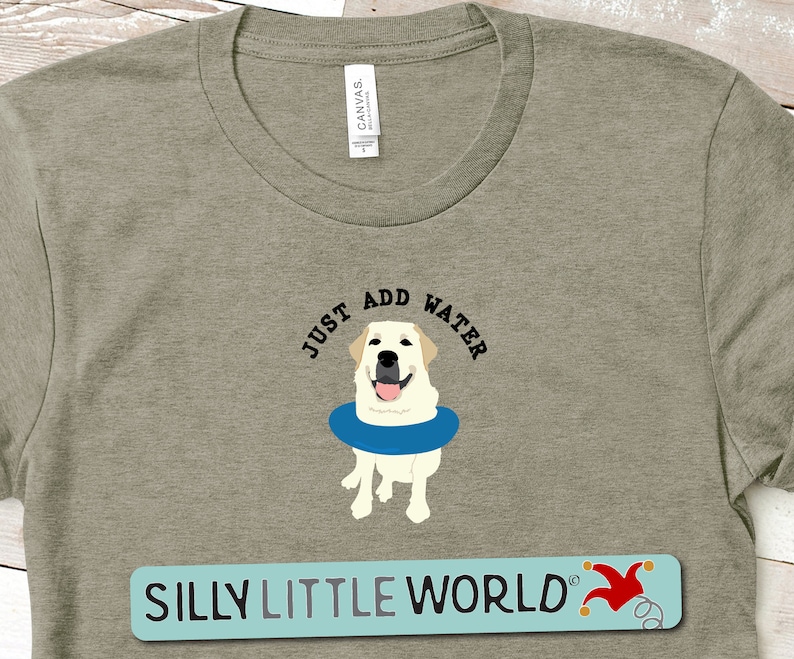 K&ouml;nnte beinhalten: Ein khakifarbenes T-Shirt mit einem wei&szlig;en Labrador Retriever, der eine blaue Schwimmweste tr&auml;gt. Der Text "Just Add Water" befindet sich &uuml;ber dem Hund. Der Text "Silly Little World" befindet sich am unteren Rand des T-Shirts.