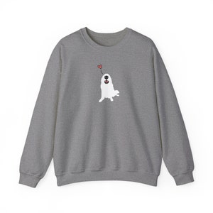 May include: A grey sweatshirt featuring a white dog illustration wearing a red heart on its head. The dog is looking up and smiling.