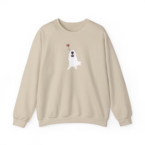 May include: A beige sweatshirt featuring a white dog illustration with a red heart above its head.