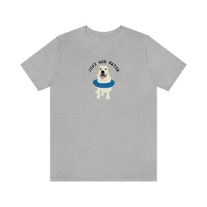 K&ouml;nnte beinhalten: Ein graues T-Shirt mit einem wei&szlig;en Hund, der eine blaue Schwimmweste tr&auml;gt. Der Text "JUST ADD WATER" ist &uuml;ber dem Hund gedruckt.