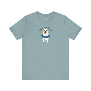 K&ouml;nnte beinhalten: Ein hellblaues T-Shirt mit einem wei&szlig;en Labrador Retriever, der einen blauen Schwimmring tr&auml;gt. Der Text "JUST ADD WATER" ist &uuml;ber dem Hund gedruckt.
