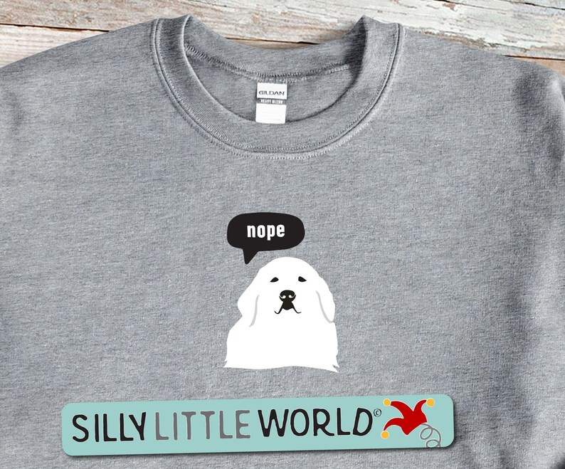 May include: Gray sweatshirt with a white dog and a speech bubble that says "nope". The text "SILLY LITTLE WORLD" is printed on a blue and yellow banner with a red jester's hat.