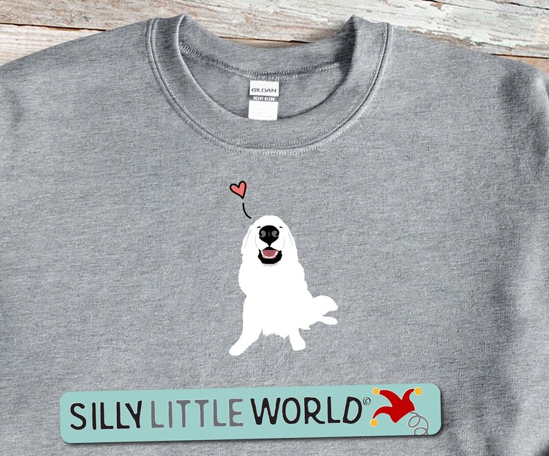 May include: Grey sweatshirt featuring a white dog illustration with a red heart above it. The text "SILLY LITTLE WORLD" is printed in blue on a light blue background with a red jester hat graphic.
