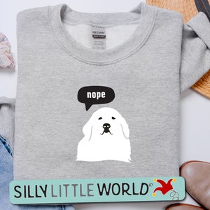 May include: Gray sweatshirt with a white dog illustration and a speech bubble that says "nope". The sweatshirt has the text "SILLY LITTLE WORLD" with a red jester hat graphic.
