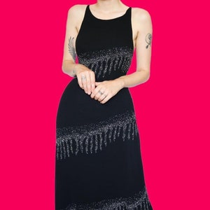 May include: A black sequined dress with a fringe hem. The dress has a sleeveless design and a scoop neckline.