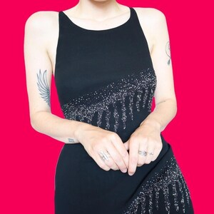 May include: A black sleeveless dress with a sequined design. The sequins are arranged in a dripping pattern.