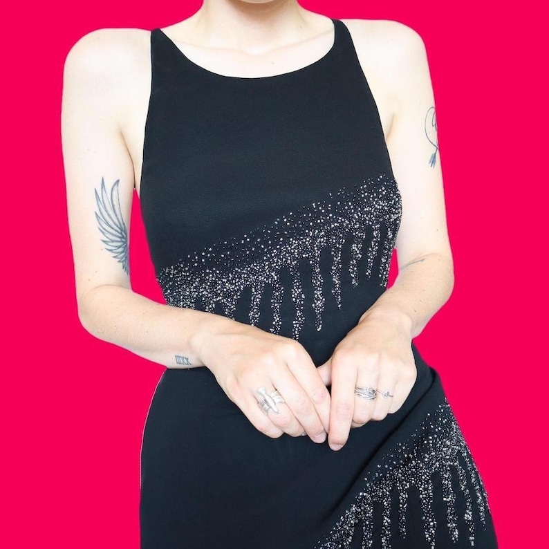May include: A black sleeveless dress with a sequined design. The sequins are arranged in a dripping pattern.