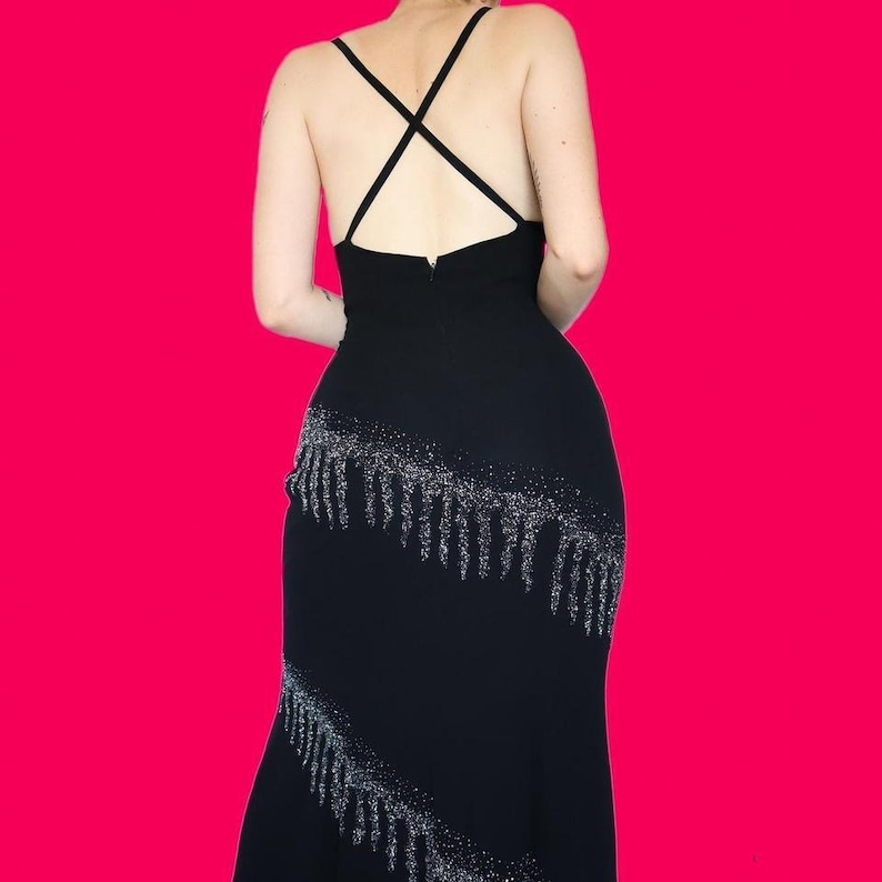 May include: A black spaghetti strap dress with a silver sequined fringe detail.