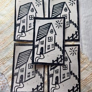 May include: Five rectangular patches with a black and white house design. Each patch features a house with a sloped roof, windows, a door, and a path leading to it. A sun and fence are also included in the design.
