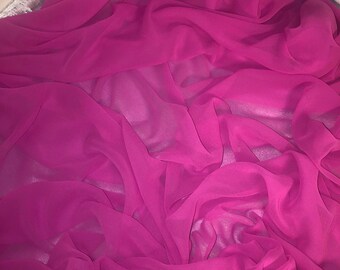 Op de afbeelding: Een close-up van een helder roze, doorschijnende stof. De stof is zacht en vloeibaar, met een delicate textuur.