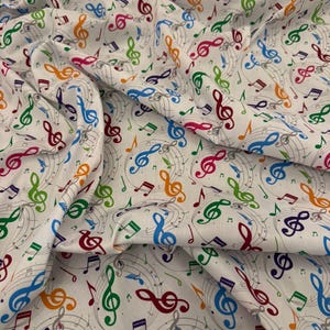 May include: White fabric with a repeating pattern of colorful musical notes and treble clef symbols. The notes are in shades of blue, green, orange, pink, and purple, with gray musical staff lines.