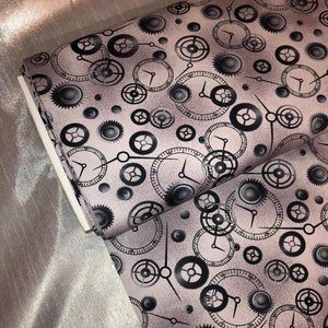 May include: A pink fabric with a repeating pattern of black gears and clock faces. The gears and clock faces are in various sizes and are arranged in a random pattern.