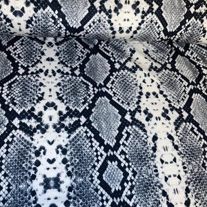 May include: White fabric with a black and grey snake skin pattern.