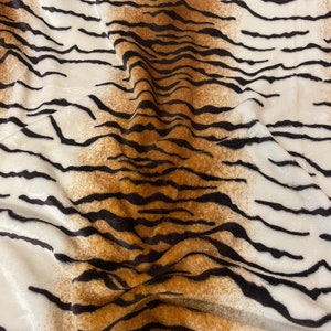 May include: White fabric with a brown and black tiger stripe pattern. The fabric is soft and plush.