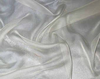 May include: A sheer white fabric with a subtle shimmer. The fabric is draped and folded, showing its texture and drape.