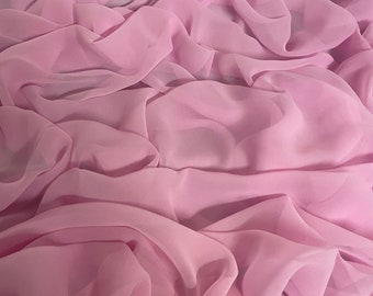May include: A soft, pink chiffon fabric with a smooth, flowing texture. The fabric is draped and folded, creating a luxurious and elegant look.